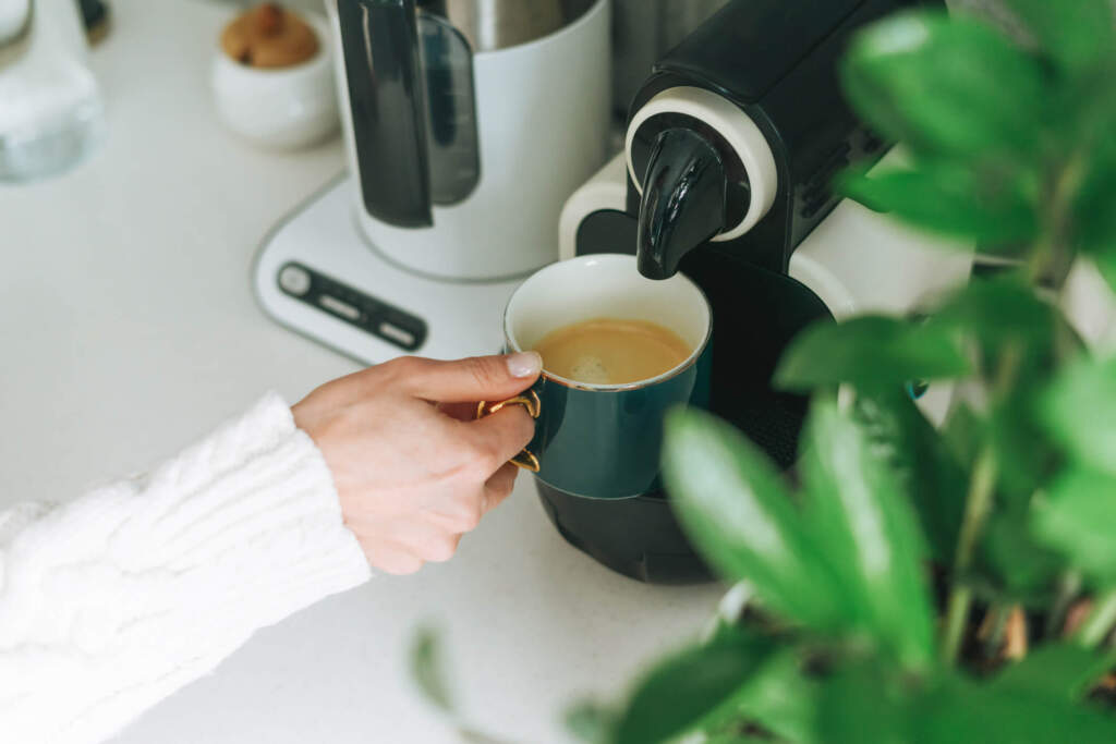 woman pours coffee from coffee machine in kitchen at home